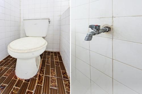 a bathroom with a toilet and a tiled floor at Hotel O Mareje Sariguna in Mataram