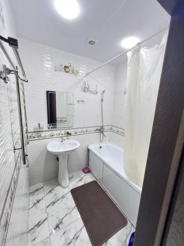 a white bathroom with a sink and a tub and a toilet at Apartment 3 in Dushanbe