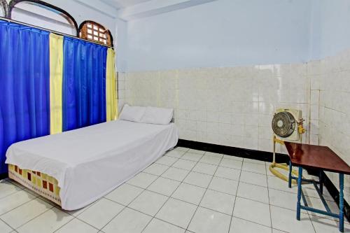 a small bedroom with a bed and a fan at Hotel O Mareje Sariguna in Mataram