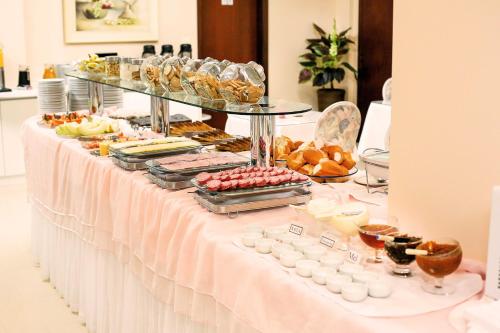 ein Buffet mit Speisen auf einem weißen Tisch in der Unterkunft Tri Hotel Xanxerê in Xanxerê
