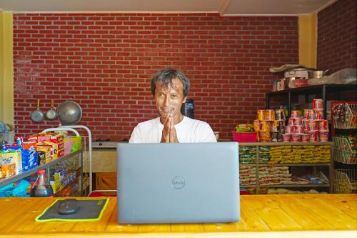 a man sitting at a table in front of a laptop at Collection O 92634 Villa Ds in Sumedang