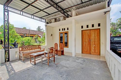 a patio with a bench and a table and chairs at Hotel O Omahku Hostel Bunkbed in Yogyakarta