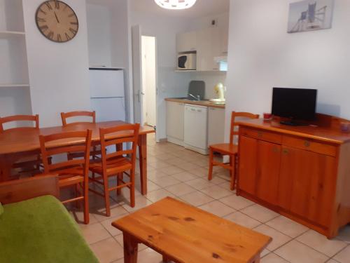 un salon avec une table et une cuisine avec une horloge dans l'établissement Appt T3 Résidence Le Cordouan 3 étoiles avec piscines et sauna, à Soulac-sur-Mer