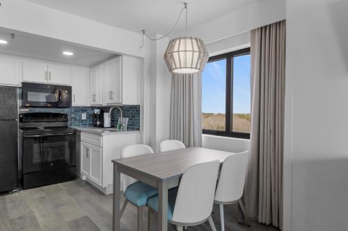 a kitchen with a table and white chairs and a window at Compass Cove in Myrtle Beach