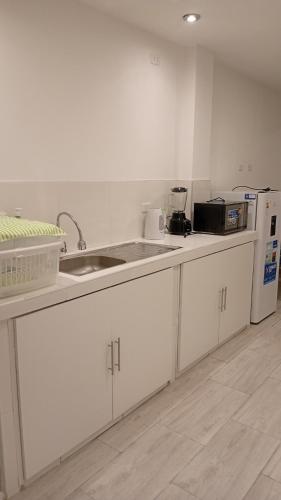 a kitchen with white cabinets and a sink and a refrigerator at Casa sunampe in Sunampe