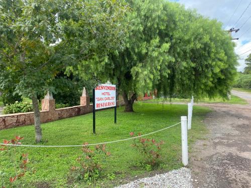 a sign sitting in the grass next to a tree at Hosteria Calamuchita in Villa del Dique