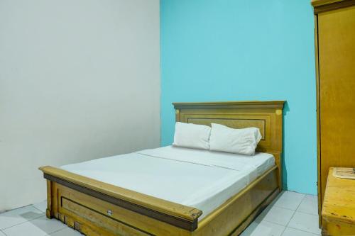 un lit dans une chambre avec un mur bleu dans l'établissement Hotel O Ervina Homestay Syariah Batakan, à Kandangan
