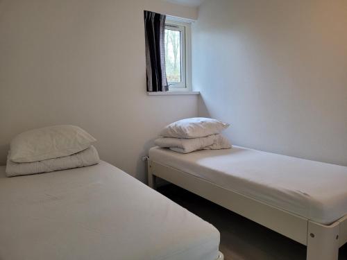 two beds in a small room with a window at Holiday Home Garden View in Tzummarum