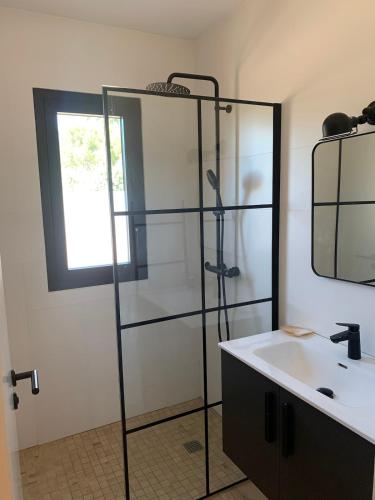 une salle de bain avec une douche en verre et un lavabo dans l'établissement Villa Les Aludes, aux Lecques