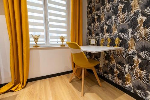 une table et une chaise jaune à côté d'une fenêtre dans l'établissement L'Éden - Centre Mulhouse - Proche Gare, à Mulhouse