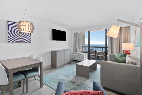 a living room with a table and a living room with a view at Compass Cove in Myrtle Beach