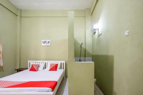 a bedroom with a bed with red pillows on it at Hotel O Onong's Homestay Near Dodikjur Rindam XIII/Merdeka in Tomohon