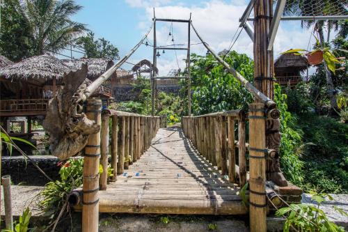 a wooden suspension bridge over a river in a resort at Hotel O Onong's Homestay Near Dodikjur Rindam XIII/Merdeka in Tomohon