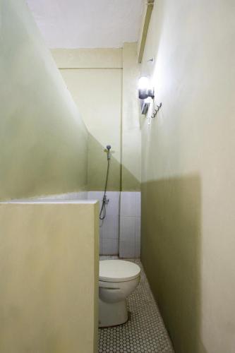 a bathroom with a toilet and a light on the wall at Hotel O Onong's Homestay Near Dodikjur Rindam XIII/Merdeka in Tomohon