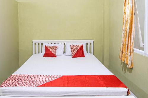 a bedroom with a bed with red and white pillows at Hotel O Onong's Homestay Near Dodikjur Rindam XIII/Merdeka in Tomohon