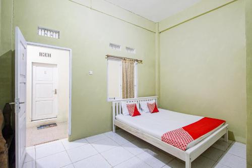 a bedroom with a bed with red pillows on it at Hotel O Onong's Homestay Near Dodikjur Rindam XIII/Merdeka in Tomohon