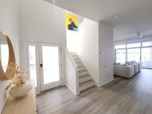 a white living room with a staircase and a couch at Miami Vice Ocean City- 5BR | Private Pool | Views in Ocean City