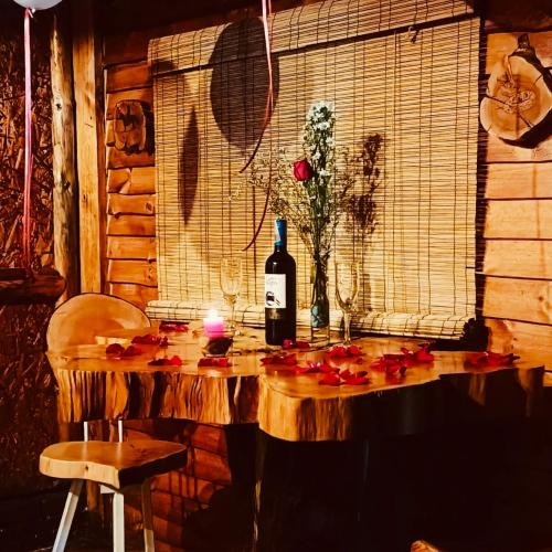 a table with a bottle of wine and a candle at Cabaña en la Calera Ciprés in La Calera