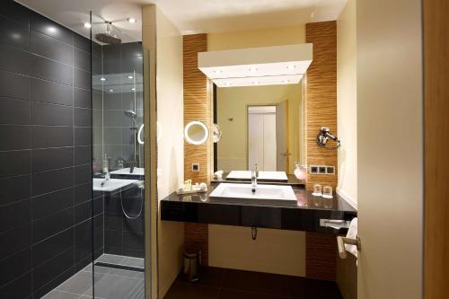 a bathroom with a sink and a shower and a mirror at Best Western Premier Park Hotel & Spa in Bad Lippspringe