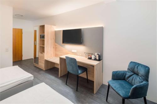 a room with a desk and two chairs and a television at Best Western Hotel Lippstadt in Lippstadt