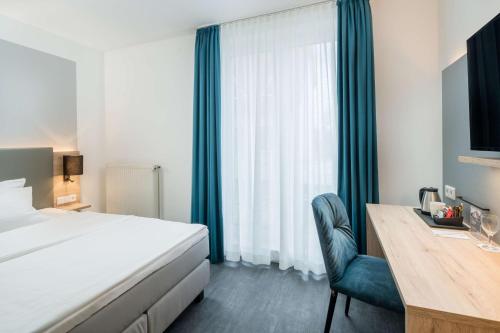 a hotel room with a bed and a desk and a bed and window at Best Western Hotel Lippstadt in Lippstadt