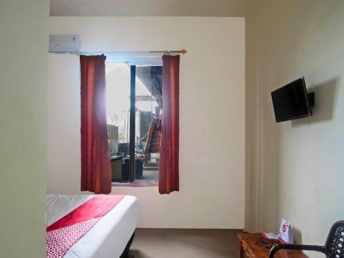a bedroom with a bed and a window with red curtains at Hotel O Miracle Kost in Manado