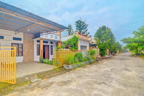 a house with a yellow gate in front of a street at Hotel O Miracle Kost in Manado