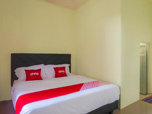 a bedroom with a large bed with two red pillows at Hotel O Miracle Kost in Manado