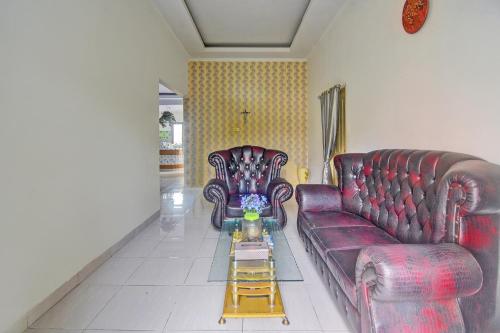 a living room with two leather couches and a coffee table at Hotel O Miracle Kost in Manado