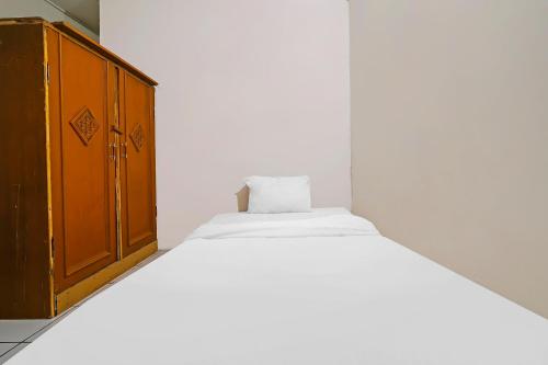 a bedroom with a bed and a wooden cabinet at OYO Life 92694 Kost Nino in Bandung