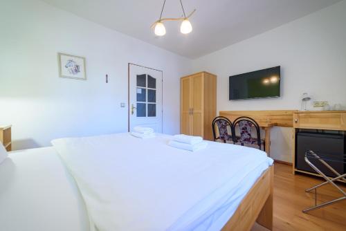 a bedroom with a large white bed and a tv at Penzion Markus - Pivovar - Brewery Frymburk in Frymburk