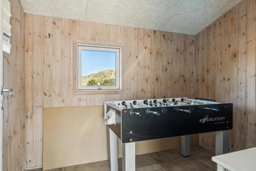 a tub in a room with wooden walls and a window at Feriehus 1115 in Hvide Sande