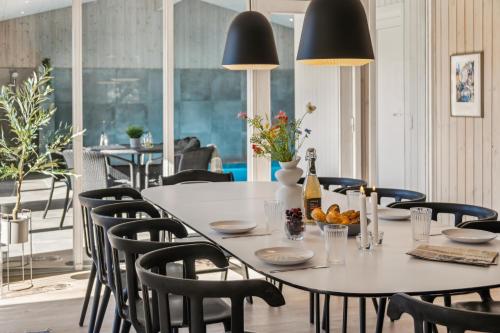 a dining room with a white table and black chairs at Feriehus 1115 in Hvide Sande