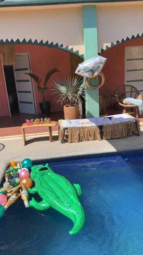 a green alligator toy in the water next to a pool at Pineapple Mansion in Paso Hondo