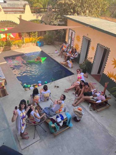 a group of people sitting around a swimming pool at Pineapple Mansion in Paso Hondo