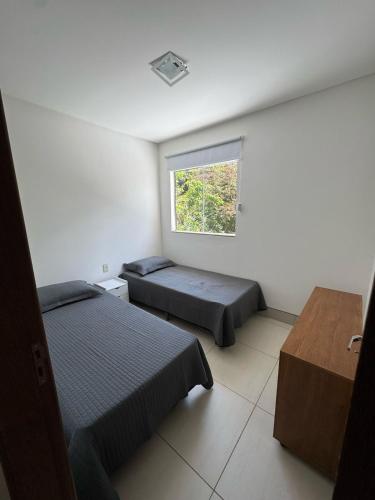 a bedroom with two beds and a window at Apartmento - Lago das Roseiras in Divinópolis