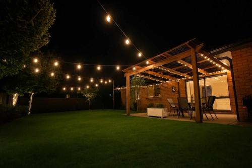 a patio with lights and a lawn at night at Huntington Honey in Hamilton