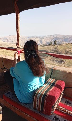a woman sitting on a ledge looking out over the desert at Dana Valley Tourism Hotel in Dana