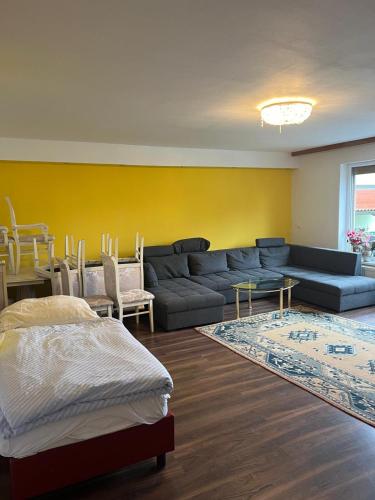 a living room with a blue couch and a yellow wall at Ferienzimmer zwischen Wien und Tulln in Tulln