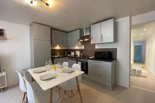 une cuisine et une salle à manger avec une table et des chaises blanches dans l'établissement Ch3-2 Les cosy Nancy by Rock in Share, à Nancy