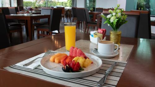 a plate of fruit on a table with a glass of orange juice at Holiday Inn Queretaro Zona Krystal by IHG in Querétaro