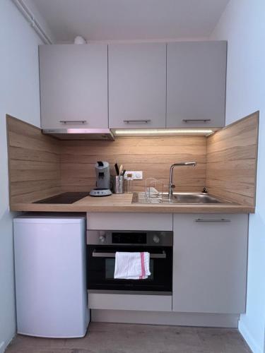 une cuisine avec des armoires blanches, un évier et une cuisinière dans l'établissement Le D'Artagnan - App 3 - Rez-de-chaussée, à Cazaubon