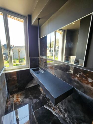 a bathroom with a black counter and a large mirror at La Villa du Clos Normand Les Petites Dalles - Maison d'hôtes in Saint-Martin-aux-Buneaux