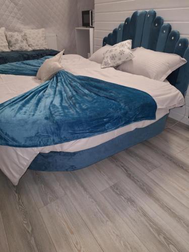 a bedroom with a blue bed with a wooden floor at Igloo Rasnov in Râşnov