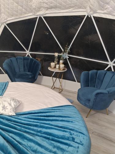 a bedroom with two blue chairs and a bed at Igloo Rasnov in Râşnov
