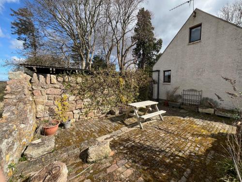 a white bench sitting in front of a stone wall at Stable Cottage by Roslin Glen in Roslin