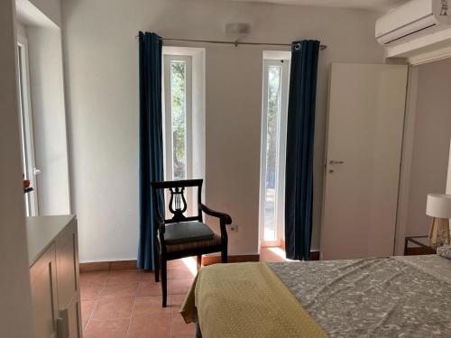 une chambre avec un lit, une chaise et des fenêtres dans l'établissement Dependence - Monte Argentario, à Isola Rossa