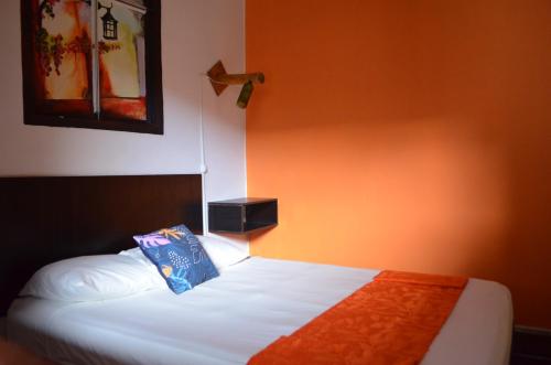 a bedroom with a bed with an orange wall at Casona Don Juan Hostel in San Gil