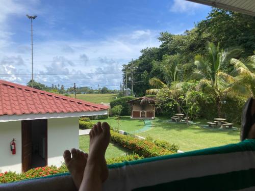 a person laying on a hammock looking out a window at a garden at Samara Beach Las Palmeras Condo with Ocean view in Sámara