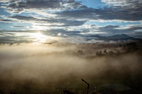 a misty sunrise in the mountains with the sun rising at Chocó 701 La Reserva- Casa Huaicundo in Nanegalito
